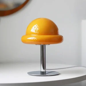 Orange glossy glass mushroom dome lamp on white side table, three-quarter angle view with chrome base