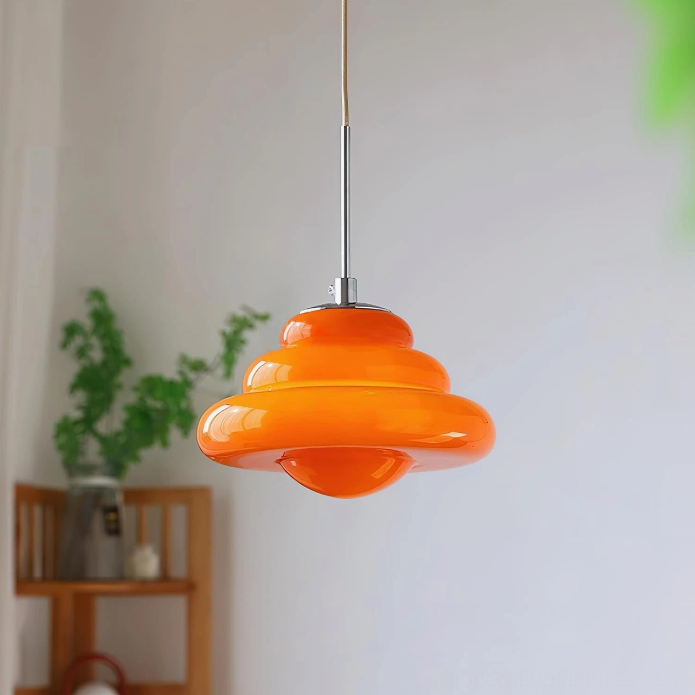 Warm orange glossy pendant light hanging in residential interior with wooden shelf and green plants