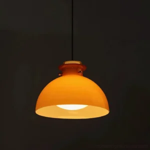 Modern orange pendant light fixture illuminated against dark background, warm light glow