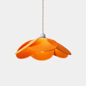Orange petal pendant light with twisted hanging cord in minimalist studio setting