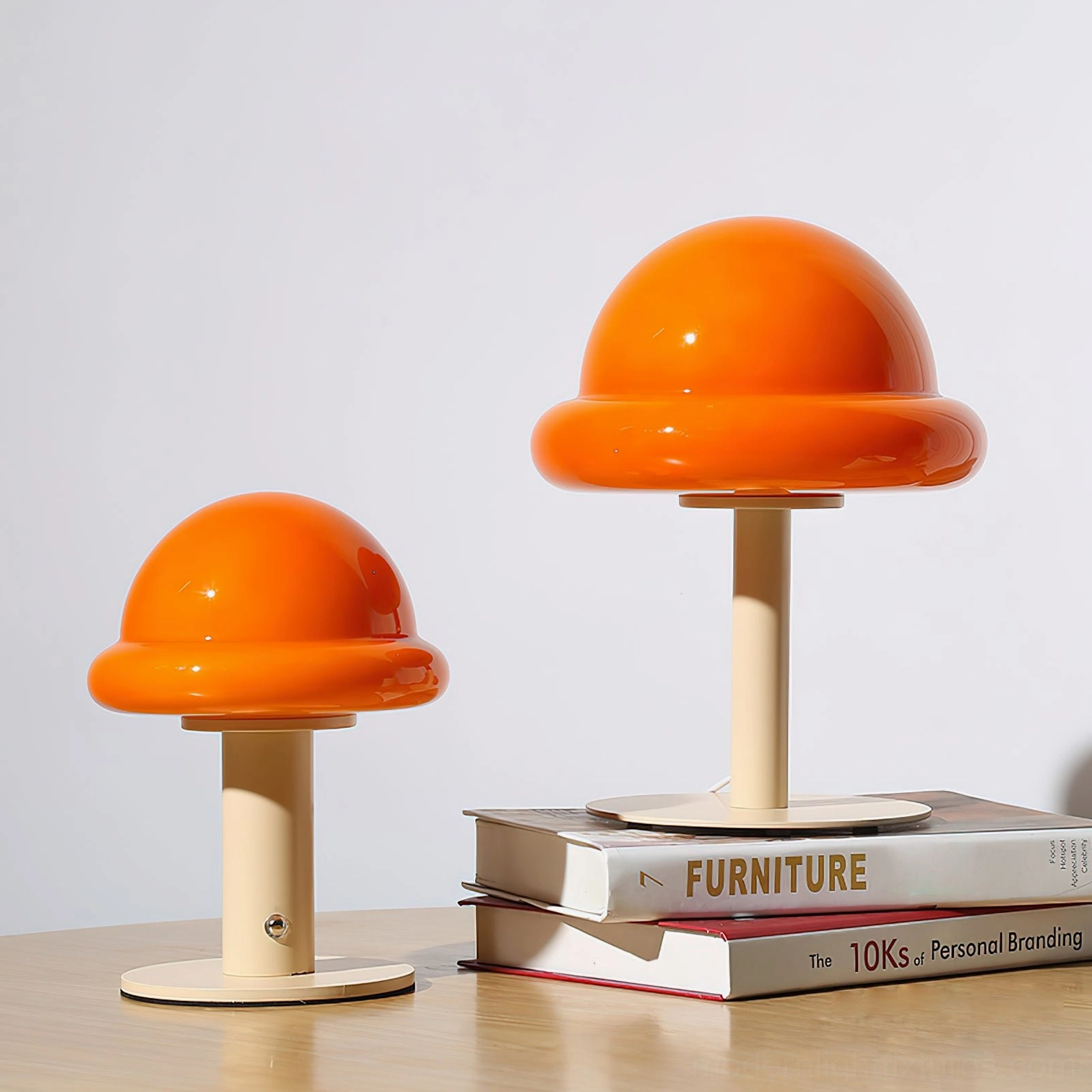 Two matching orange cordless mushroom table lamps stacked arrangement on wooden table with decorative books