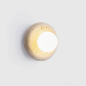 Minimalist orb wall sconce with beige travertine and white glass, glowing warm light, studio shot