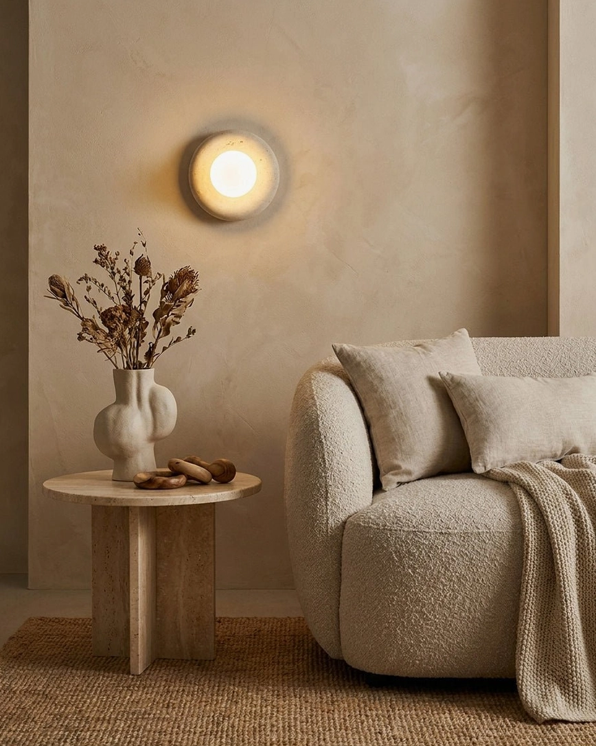 Orb wall sconce in relaxed lounge setting with sofa and decorative side table, warm ambient glow
