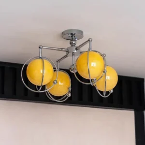 Side close-up of orbital ceiling lamp showing polished chrome hardware and yellow glass shades
