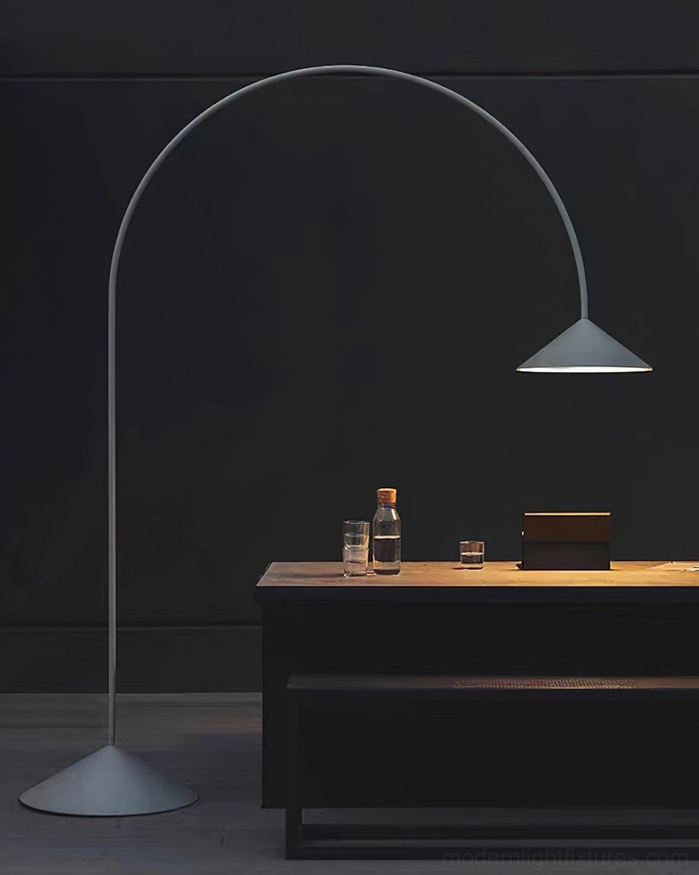 Grey matte Orbitas arc floor lamp in modern home office desk area with warm ambient lighting