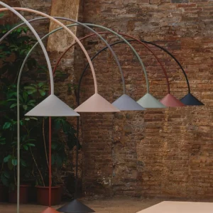 Set of Orbitas arc floor lamps in assorted pastel matte colors on exposed brick wall outdoor background