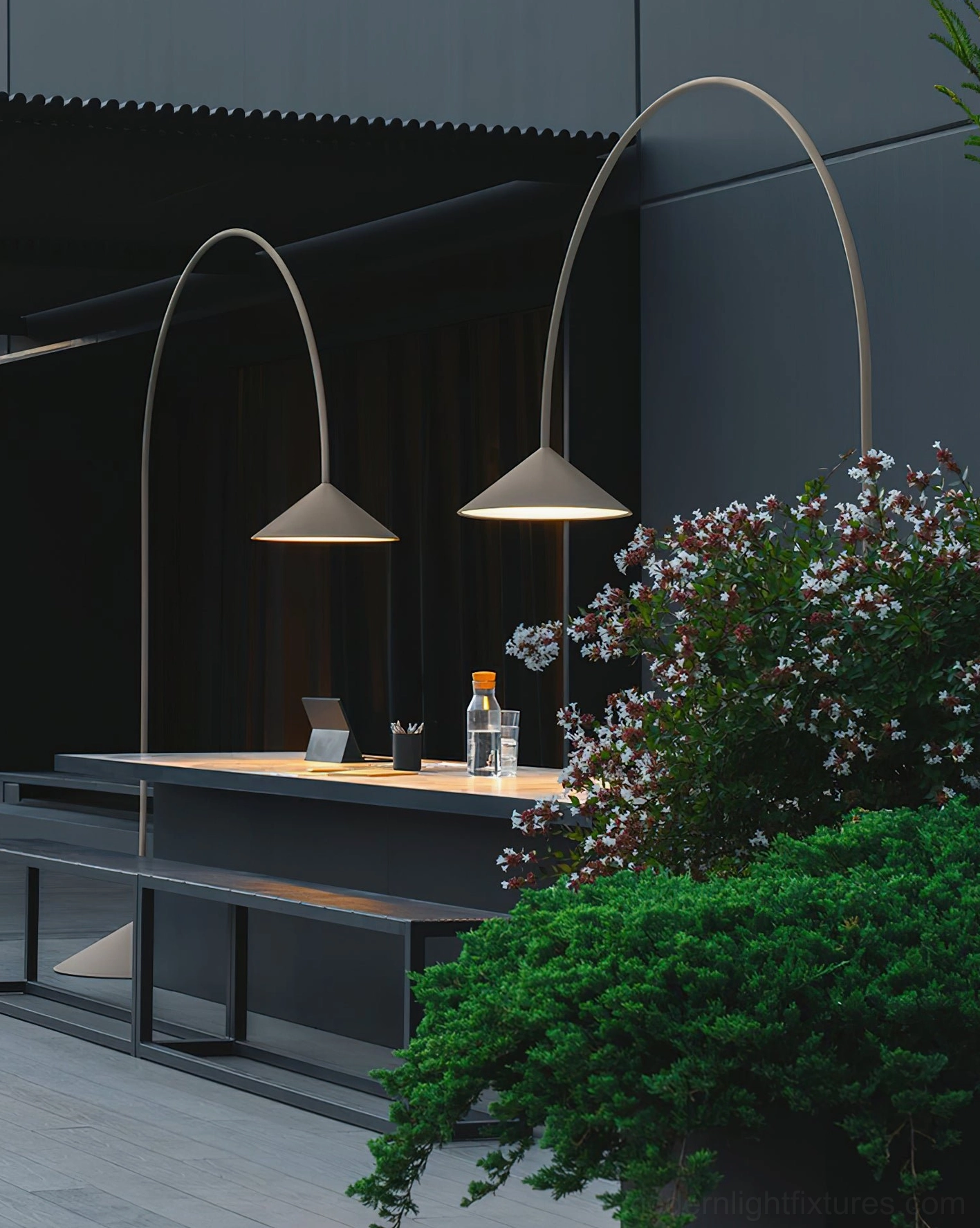 Two Orbitas arc floor lamps in neutral matte finishes on outdoor dining terrace with minimalist industrial aesthetic