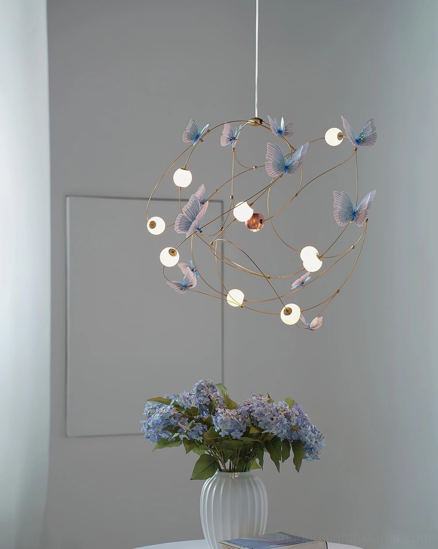 Modern pendant chandelier with organic butterfly-inspired brass framework and soft glowing sphere elements for living spaces