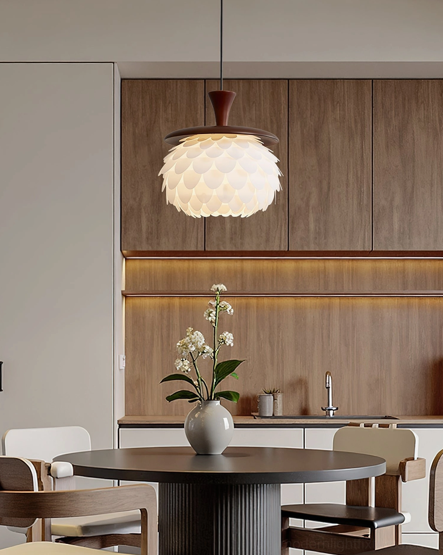 Contemporary petal ceiling light installed in modern wooden kitchen above dark round dining table with potted orchid decoration