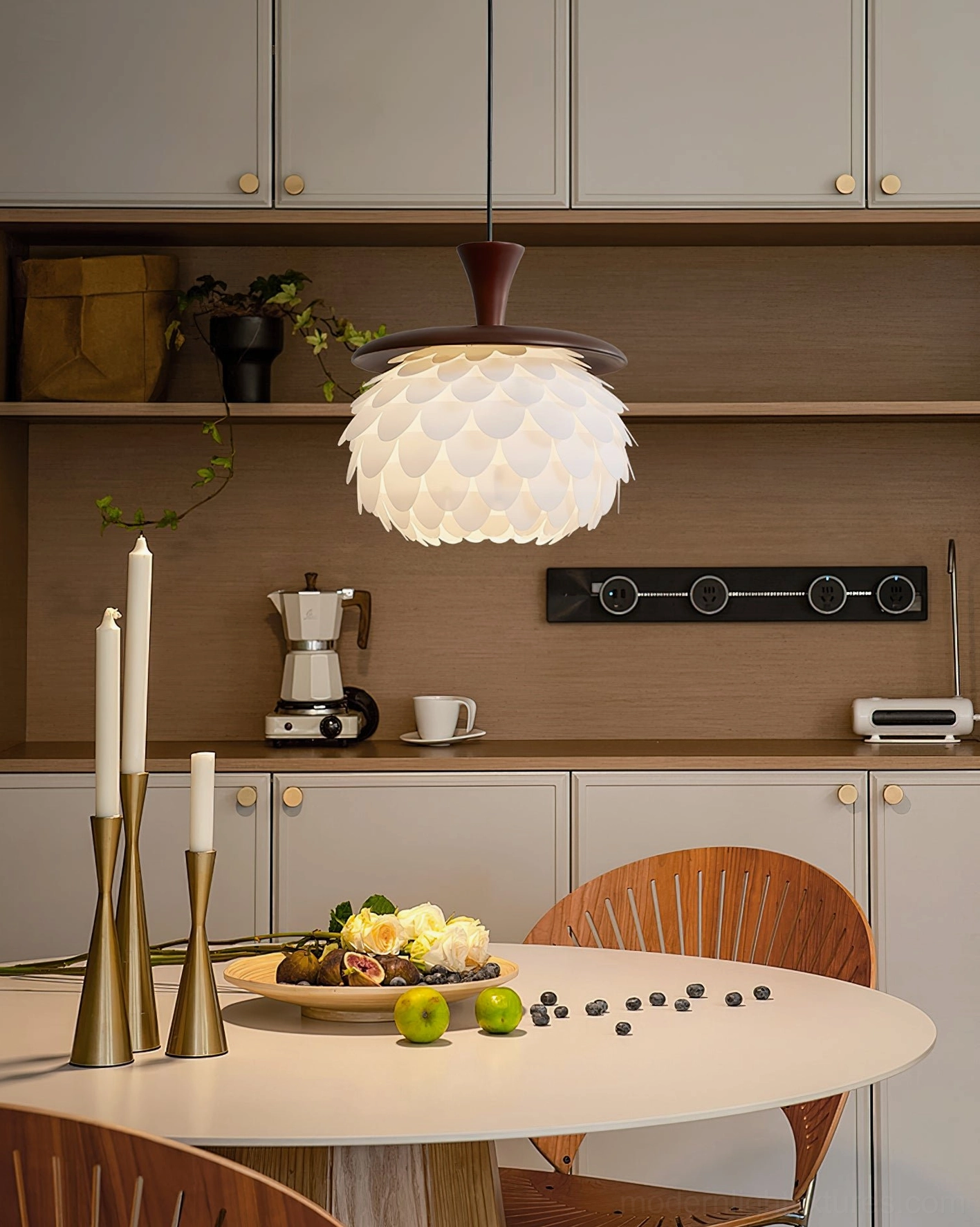 Sculptural petal pendant light installed in contemporary minimalist kitchen dining area with light wood cabinets and round table