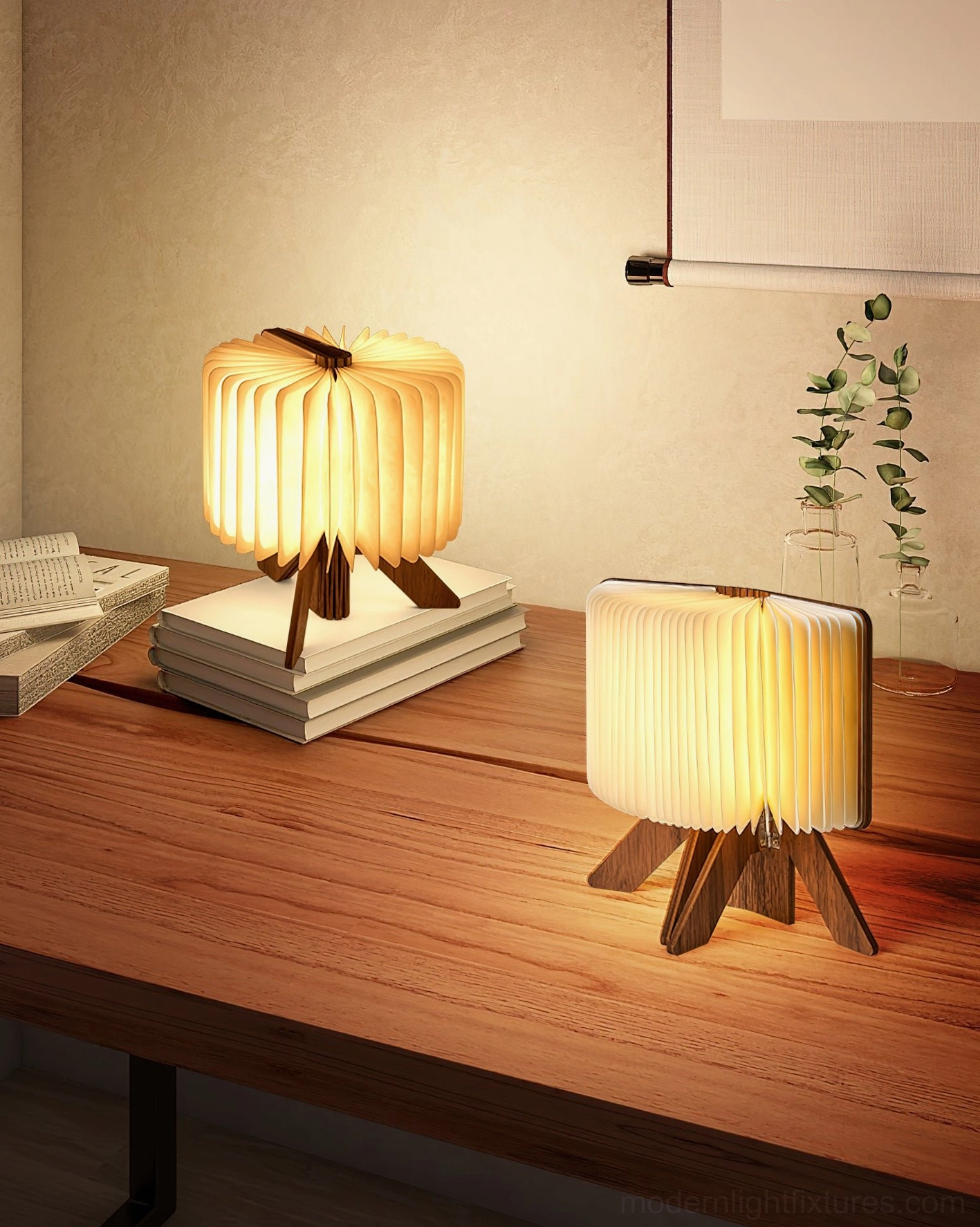 Pair of origami wood table lamps on home wooden desk with books and eucalyptus plants, warm interior lighting