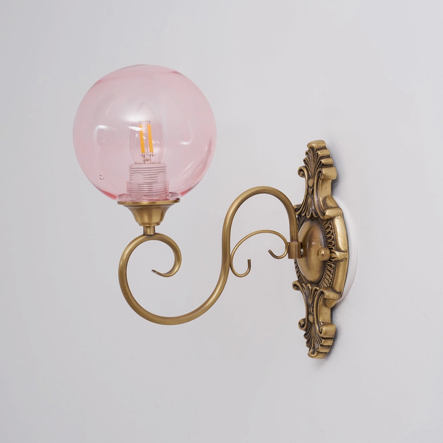 Ornate brass backplate and arm of vintage wall sconce, baroque metalwork detail