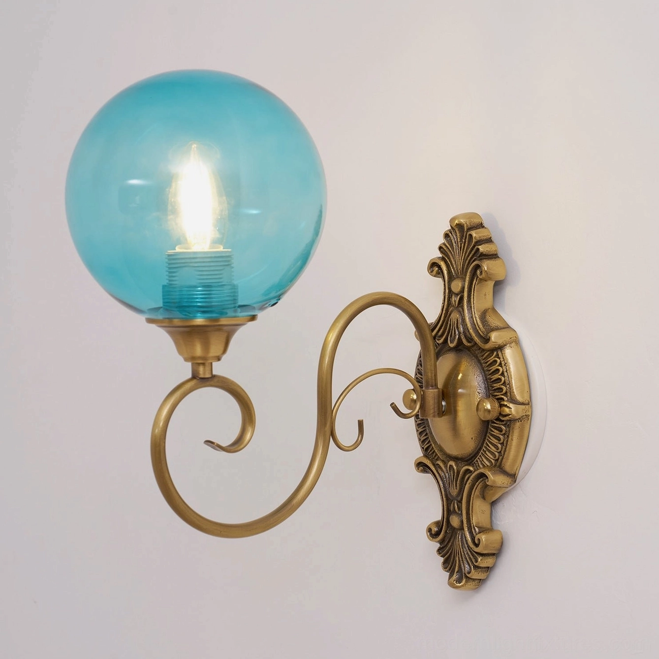 Close-up of ornate brass wall sconce details and patina finish, vintage metalwork texture