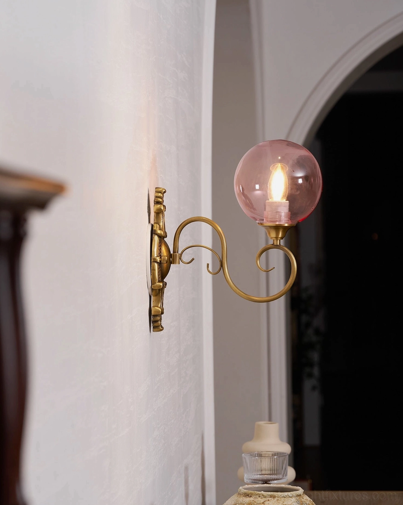 Ornate brass wall sconce lighting effect showing glass globe illumination, warm vintage glow