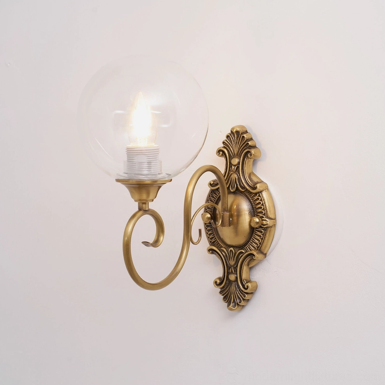 Ornate brass wall sconce side view showing curved arm profile and glass globe proportion