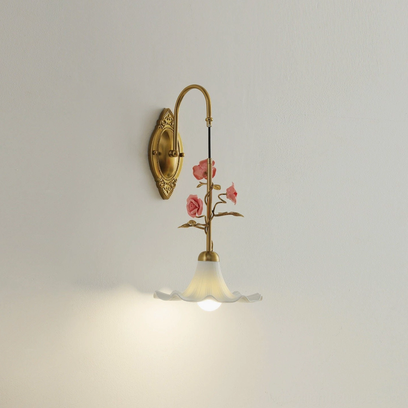 Ornella wall lamp three-quarter angle view showing ornate brass backplate and warm light emission