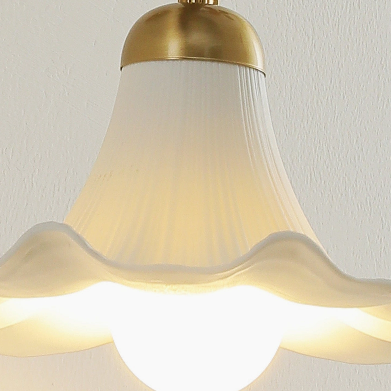 Ornella frosted glass shade close-up detail with ruffled texture and brass gold top cap illuminated