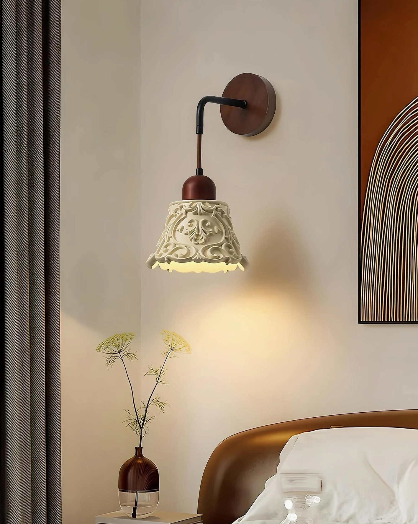 Ornella wall sconce positioned as master bedroom bedside lighting, creating warm downlighting above wall art display