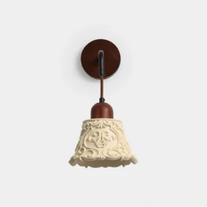 Ornella carved resin wall sconce with ivory shade and walnut wood mounting bracket, front studio view showcasing intricate floral relief patterns