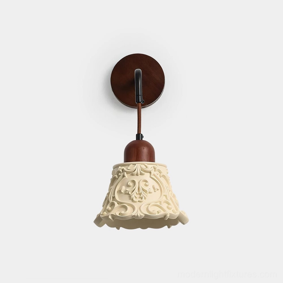 Ornella carved resin wall sconce with ivory shade and walnut wood mounting bracket, front studio view showcasing intricate floral relief patterns