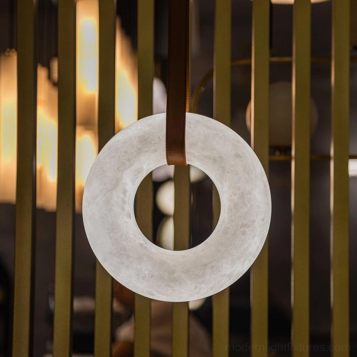 Side view of Oslo alabaster ring pendant showing natural stone radiance and leather suspension system in interior space
