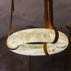 Close-up detail of alabaster ring pendant light showing brown leather straps and natural marble veining with warm glow