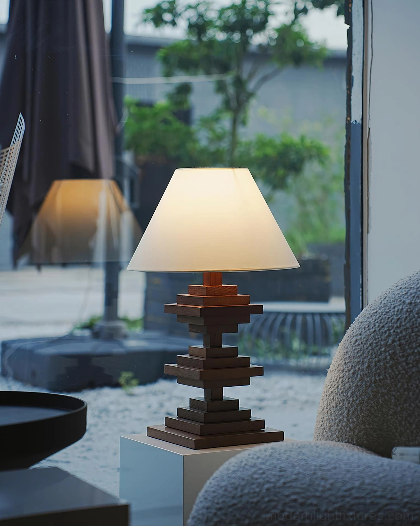 Contemporary wooden tower table lamp on outdoor patio displaying architectural design with white cube stand and natural lighting