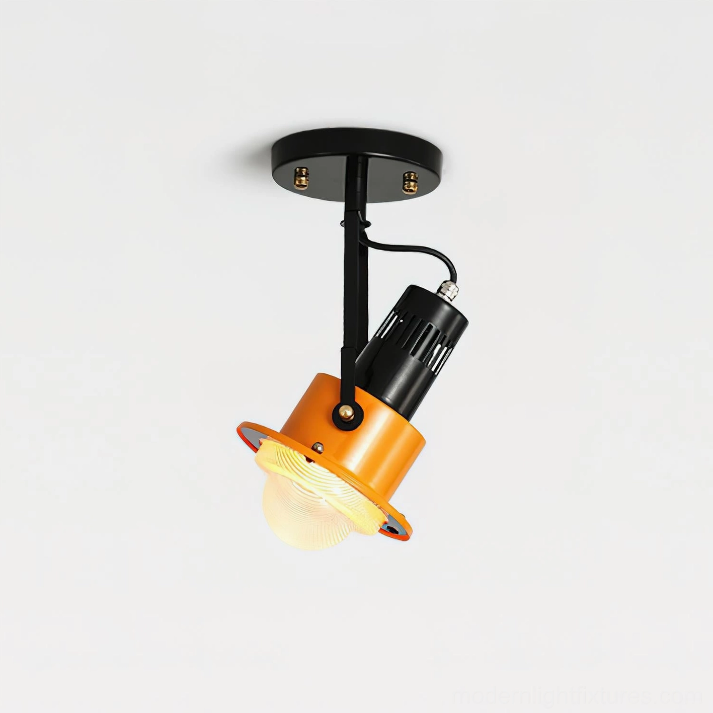 Adjustable overhead spotlight with glowing warm light, black metal construction, orange acrylic shade detail