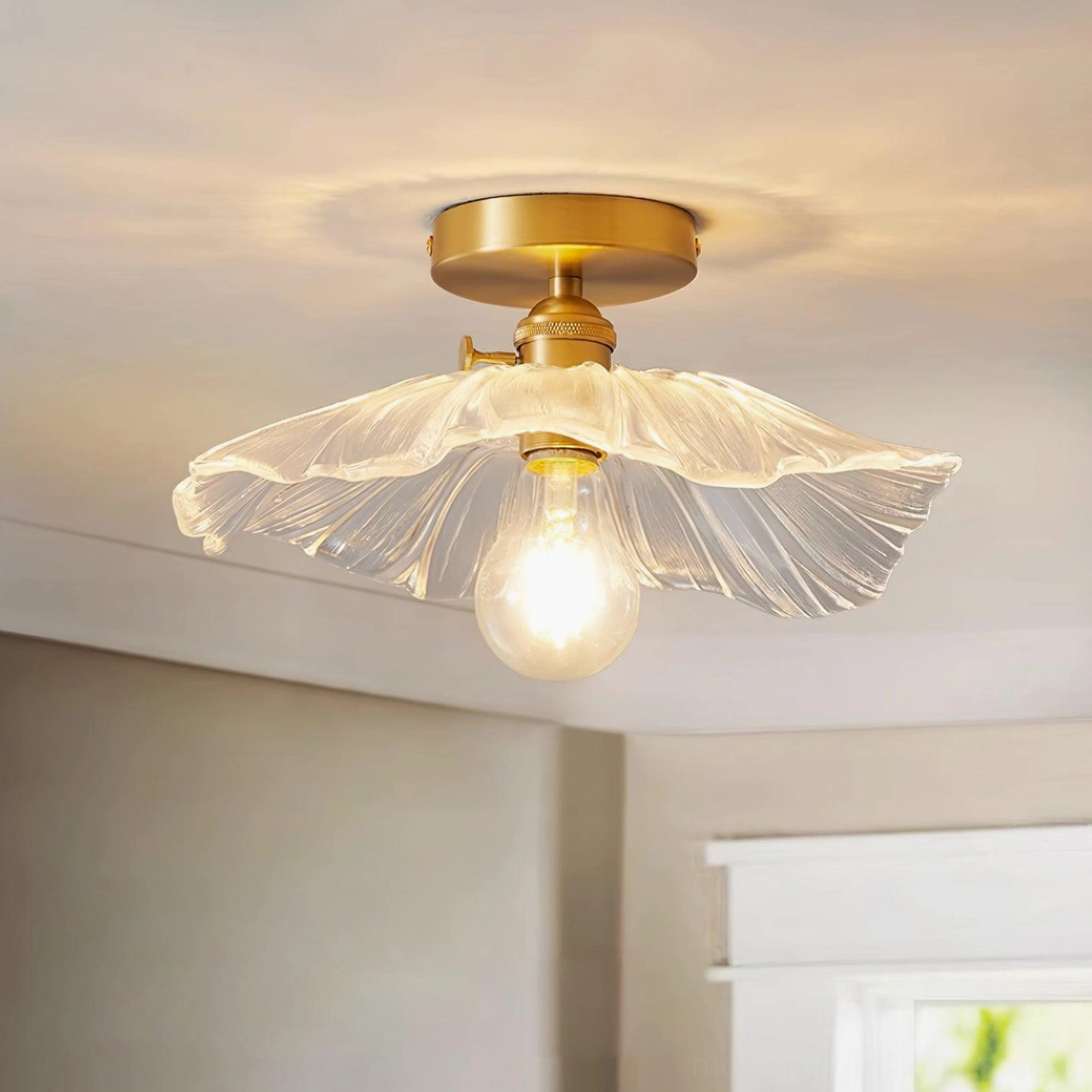 Overhead view of ruffled glass ceiling fixture showing fluted clear glass shade and brass mount with illuminated vintage bulb