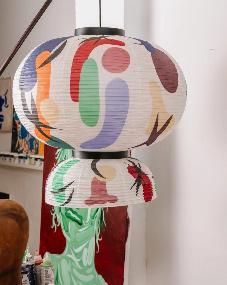 Oversized printed paper pendant lamp low-angle close-up showing layered lantern construction with abstract multicolor prints in home art setting
