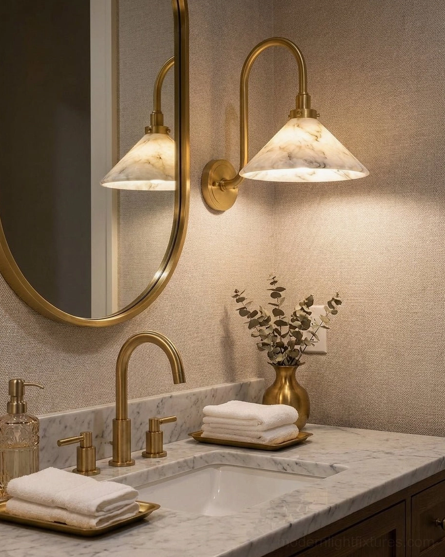 Pair of Lunelle alabaster wall sconces flanking brass mirror above bathroom vanity countertop