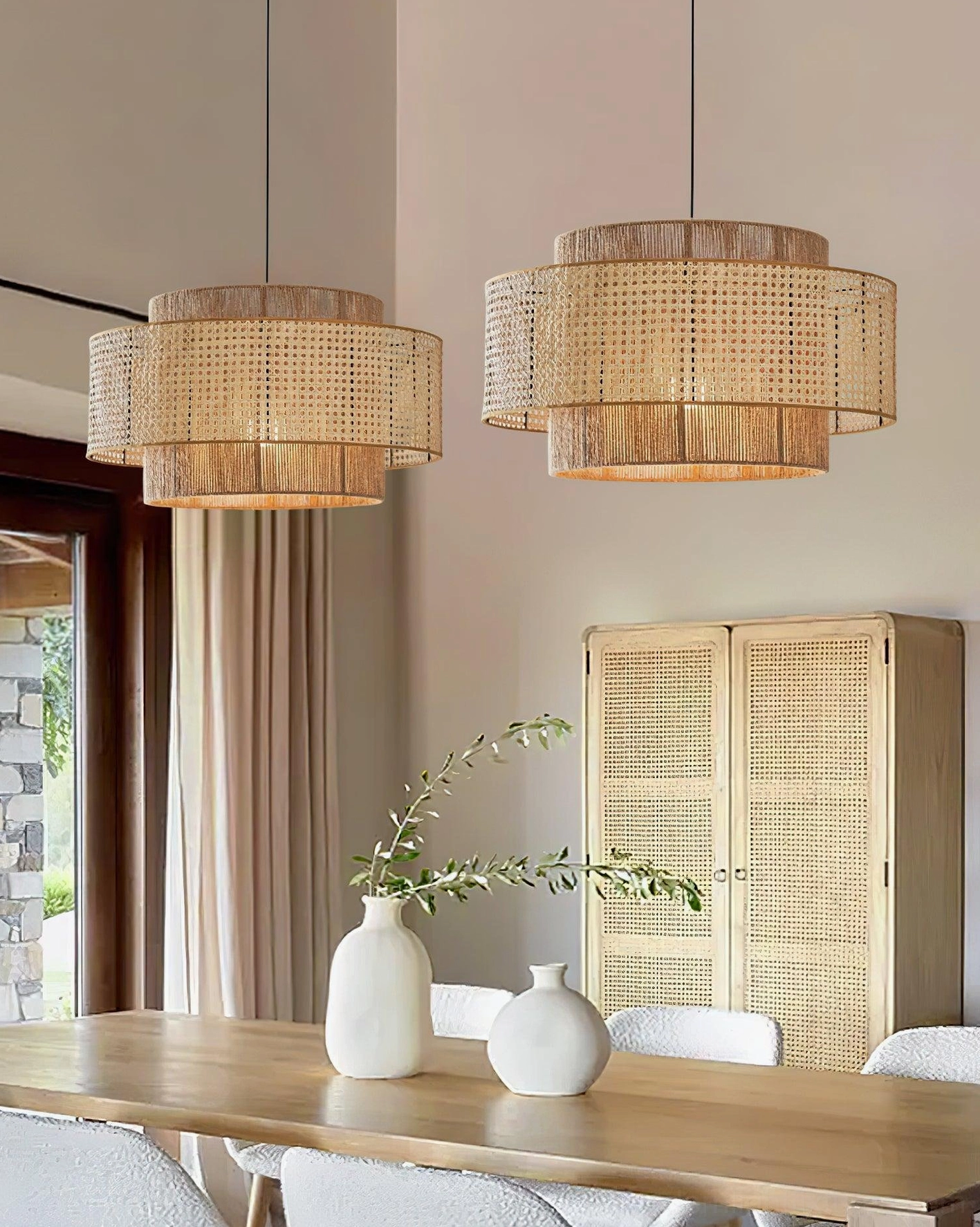 Matching pair of boho rattan weaving pendant lamps over wooden dining table with rattan cabinet, side view showcasing dual fixtures