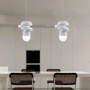 Two modern pendant lights with layered white discs suspended over dining table with rattan chairs, contemporary interior design