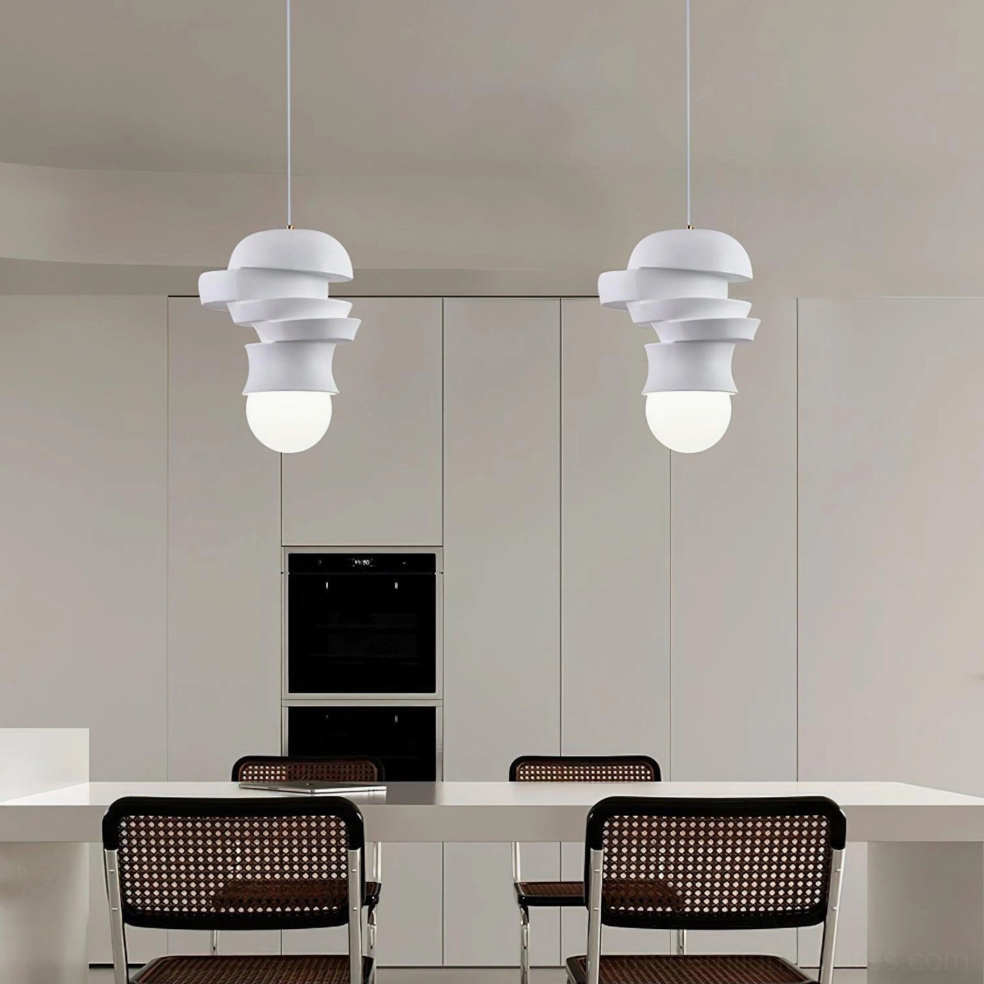 Two modern pendant lights with layered white discs suspended over dining table with rattan chairs, contemporary interior design