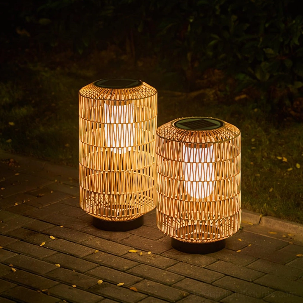 Pair of cylindrical woven rattan outdoor lamps on brick paved garden path at night