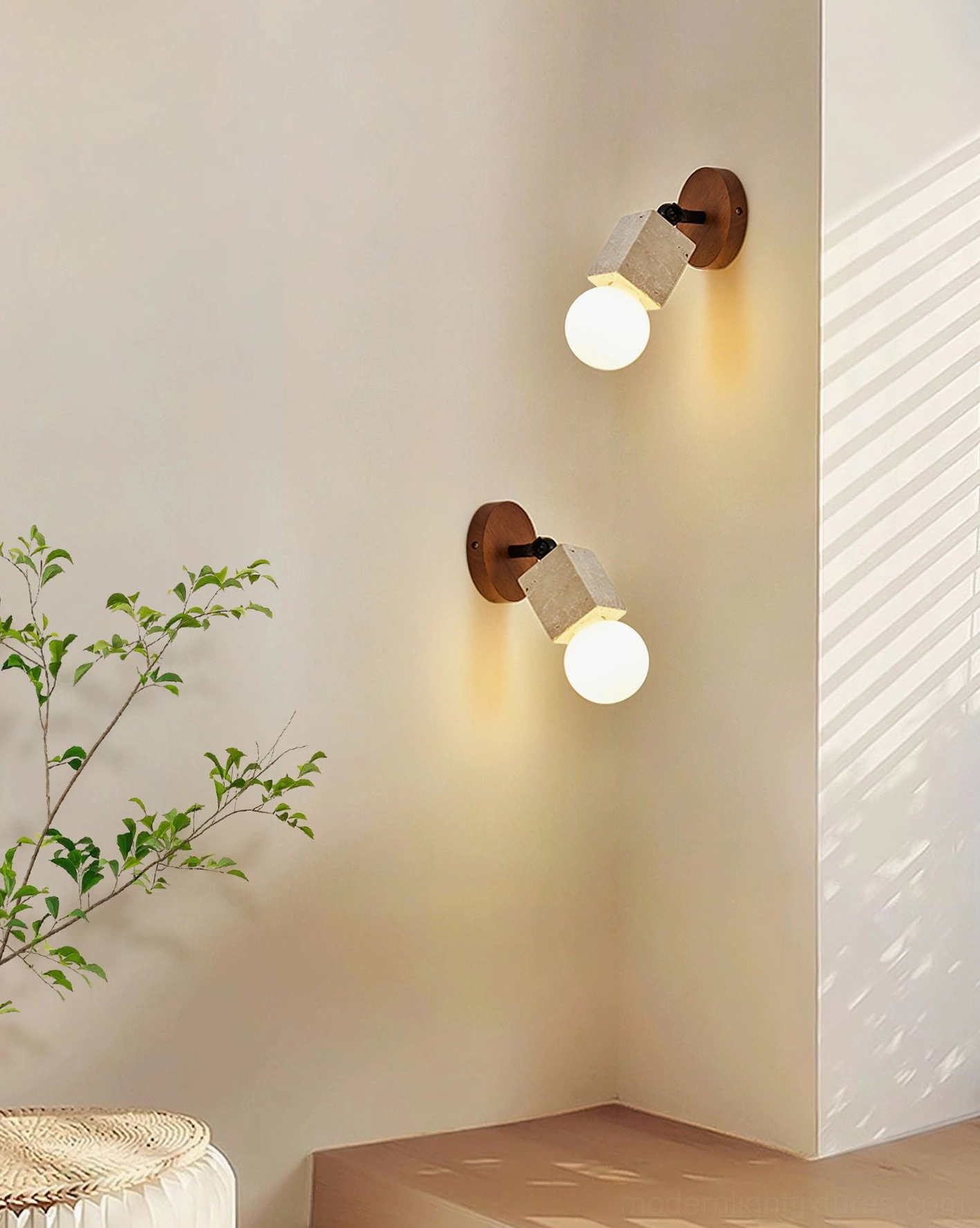 Pair of bezel travertine wall sconces in minimalist residential corner with green plant decoration