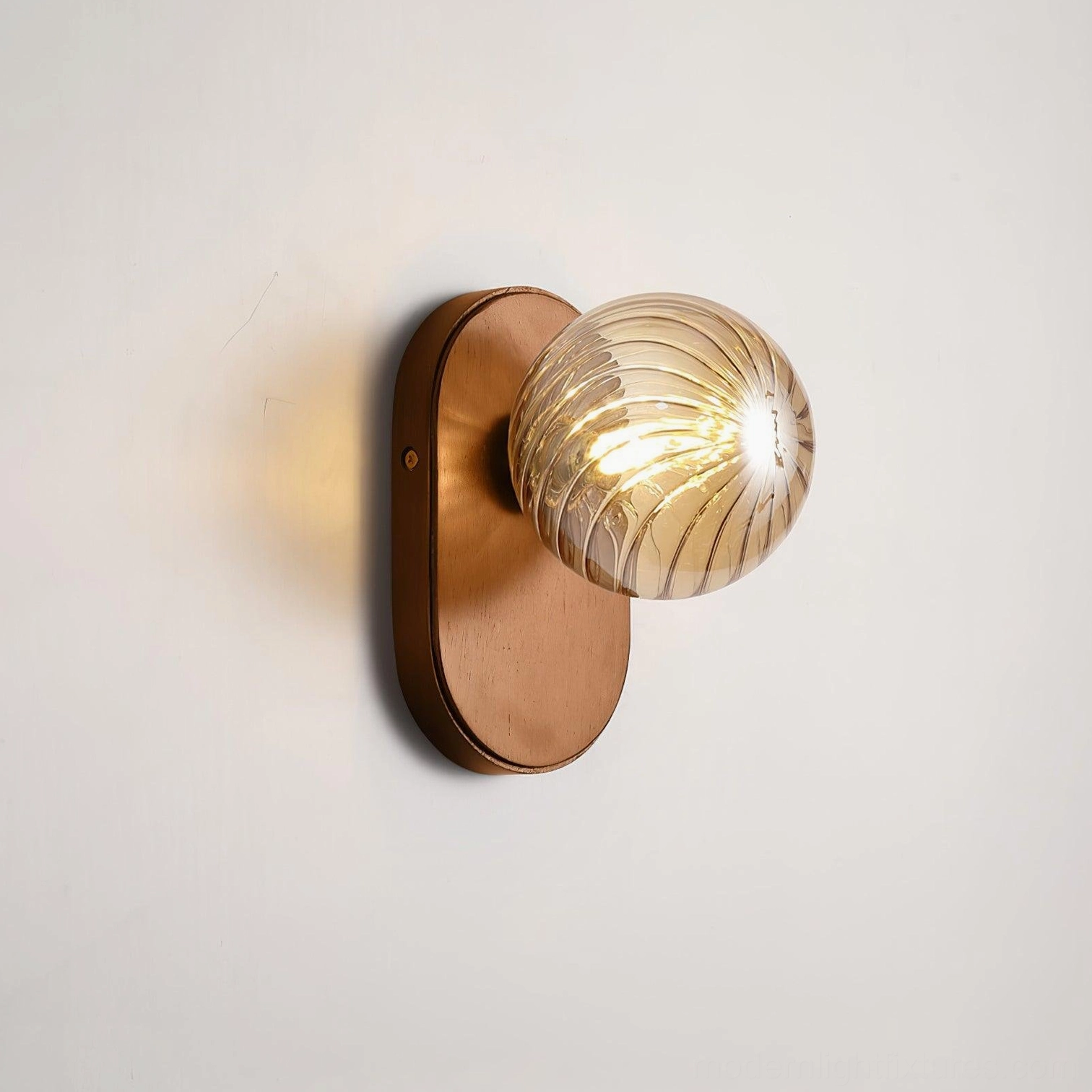 Lit Paola orb wall lamp glowing amber glass showing light and shadow play effect
