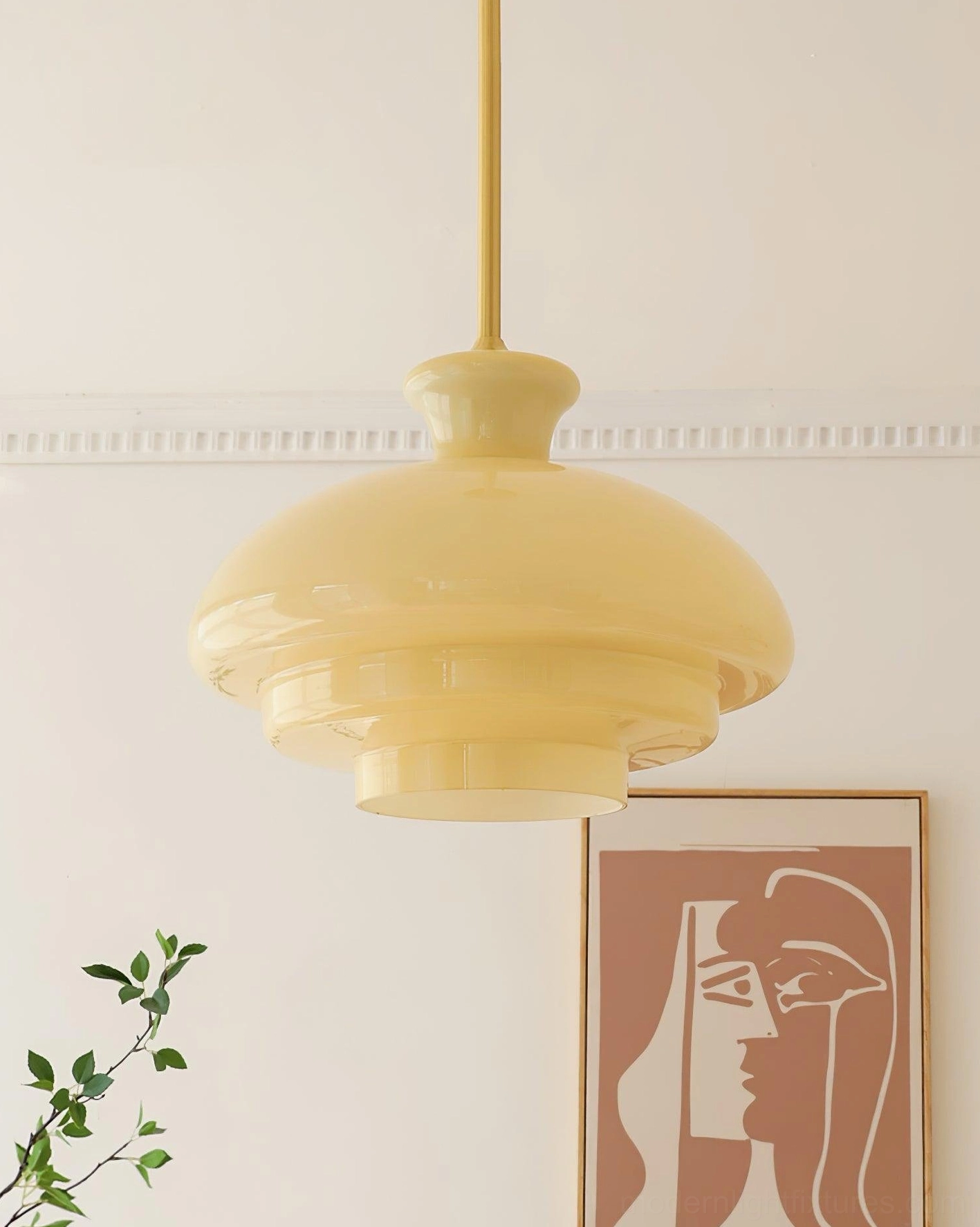 Paolina creamy beige tiered glass pendant light hanging in residential space with crown moulding and green plants, side angle view