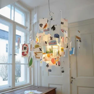 Modern paper pendant light installed in contemporary residential room corner with mixed paper card arrangement