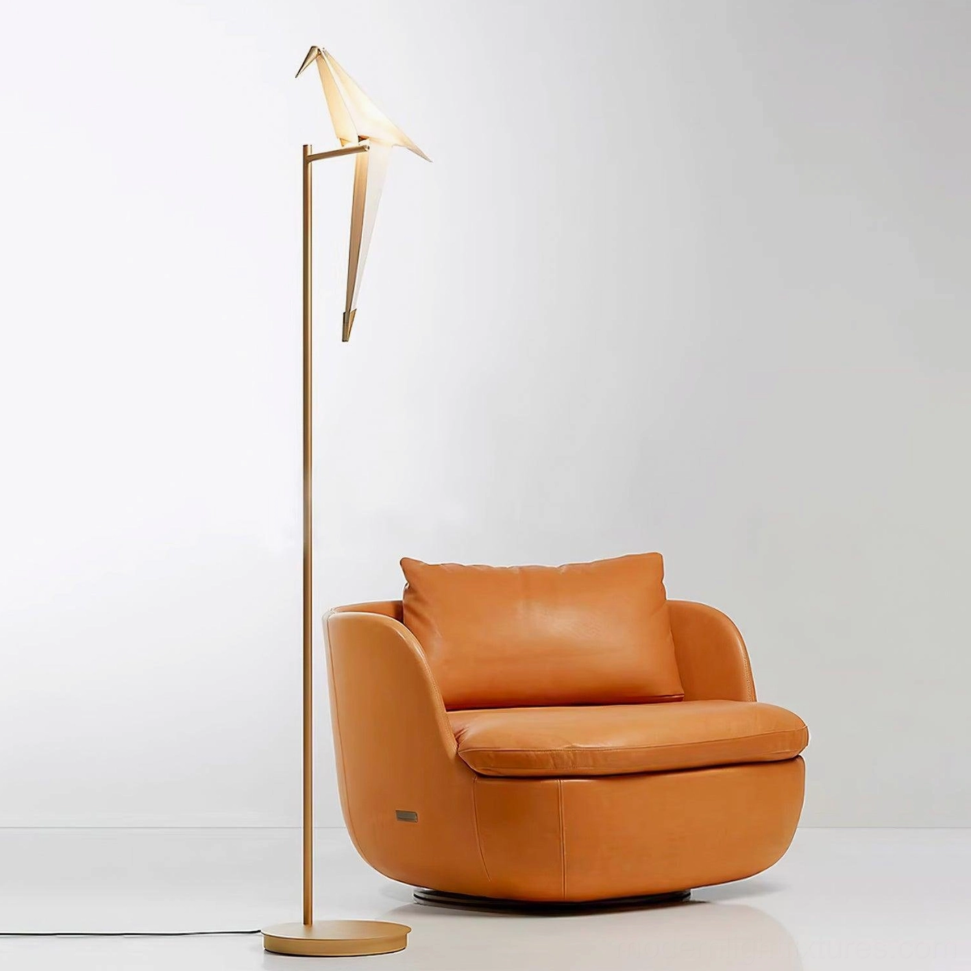 Modern paper crane floor lamp in living room setting with leather armchair, three-quarter angle view
