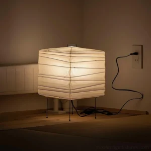 Geometric folded paper cube lamp displayed on bedroom dresser with decorative books and accessories
