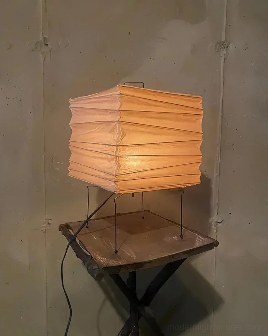 Contemporary paper cube table lamp with warm glow on industrial rustic concrete side table
