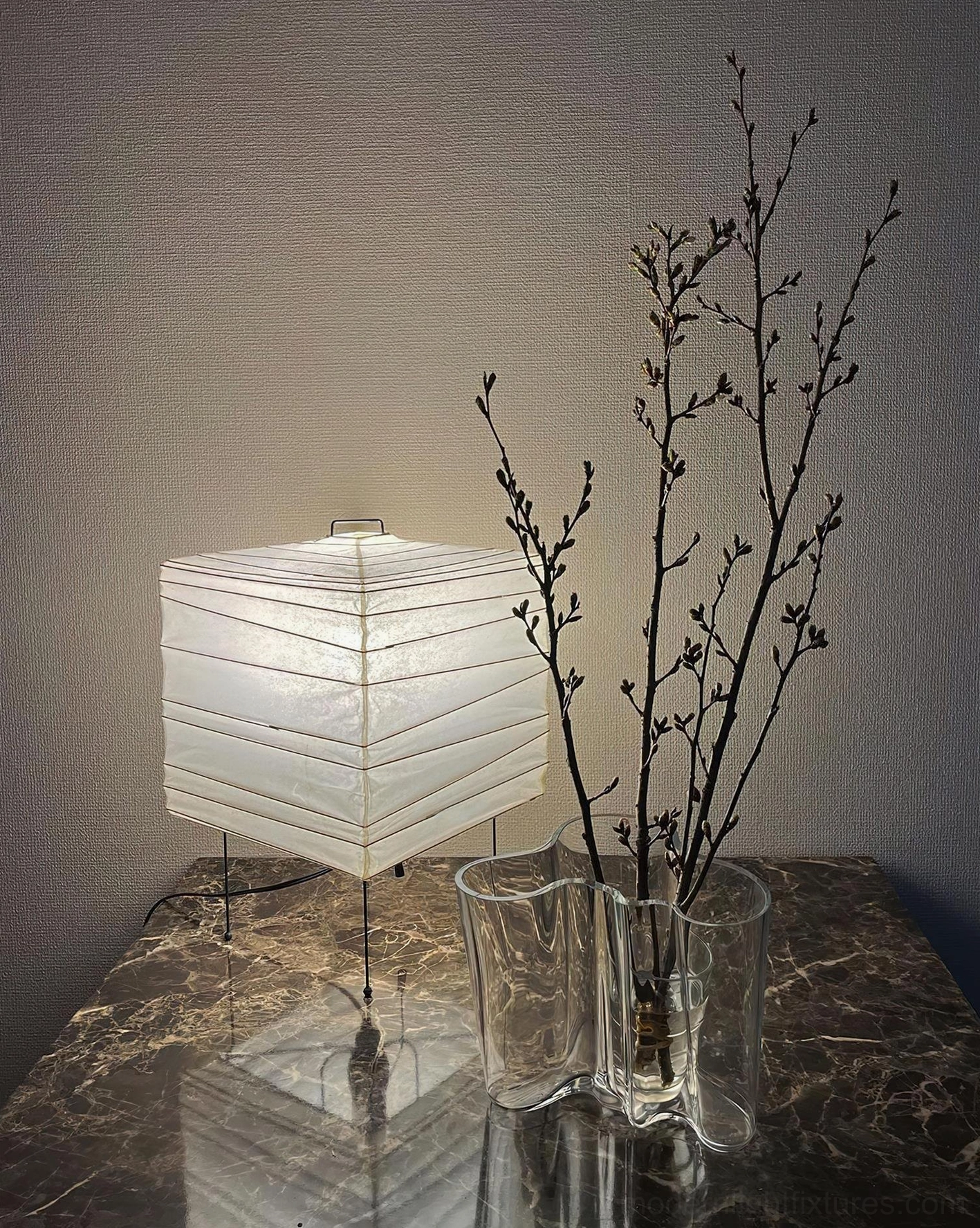 Minimalist cube paper table lamp with warm ambient lighting on dark wooden side table in bedroom