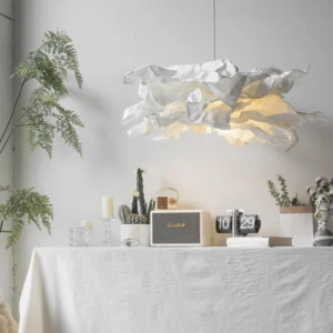 Handcrafted paper pendant lamp illuminated above Nordic-style dining table with green plants and warm ambient lighting
