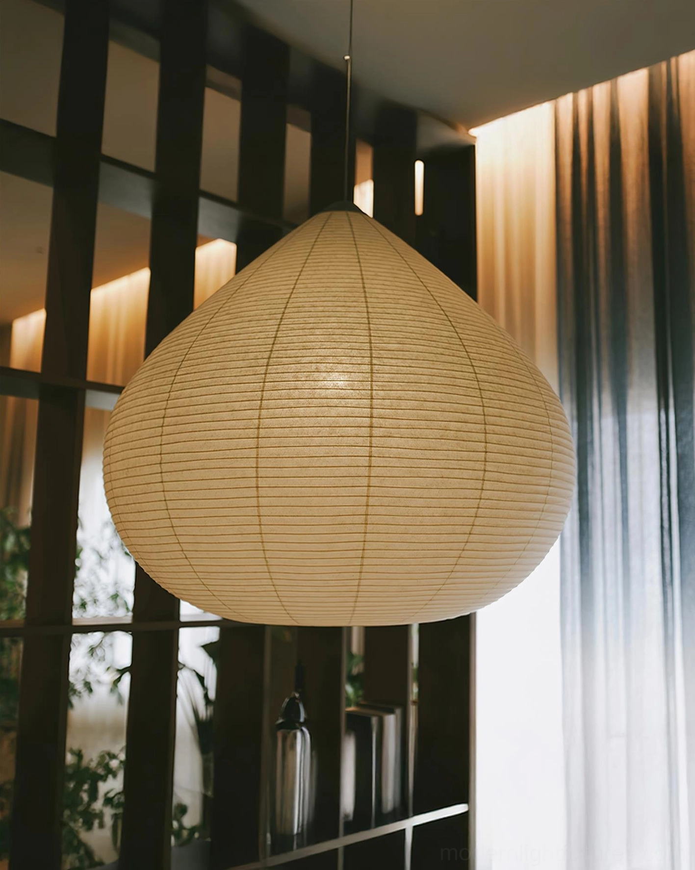 Low angle view of ribbed paper pendant lamp with tan shade in modern lounge setting