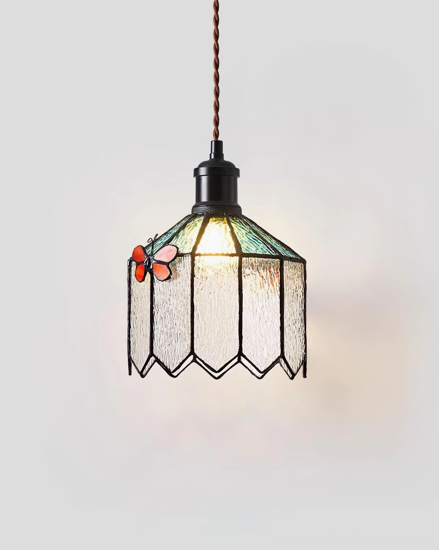 Papilune stained glass pendant lamp illuminated three-quarter view showing warm glass glow and artistic detail