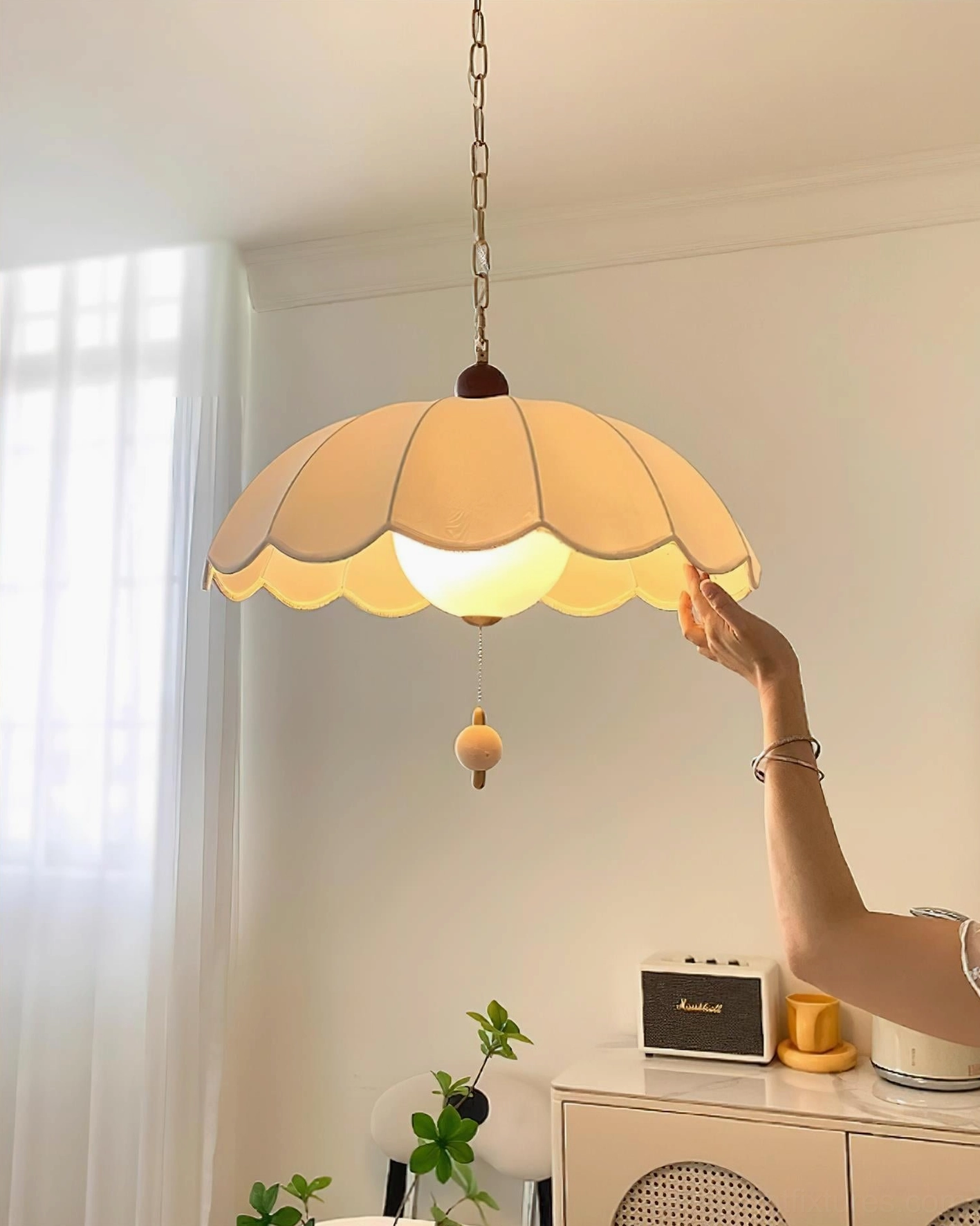 Illuminated Paralune pendant lamp with warm glowing light, hand interaction showing soft ambient lighting quality