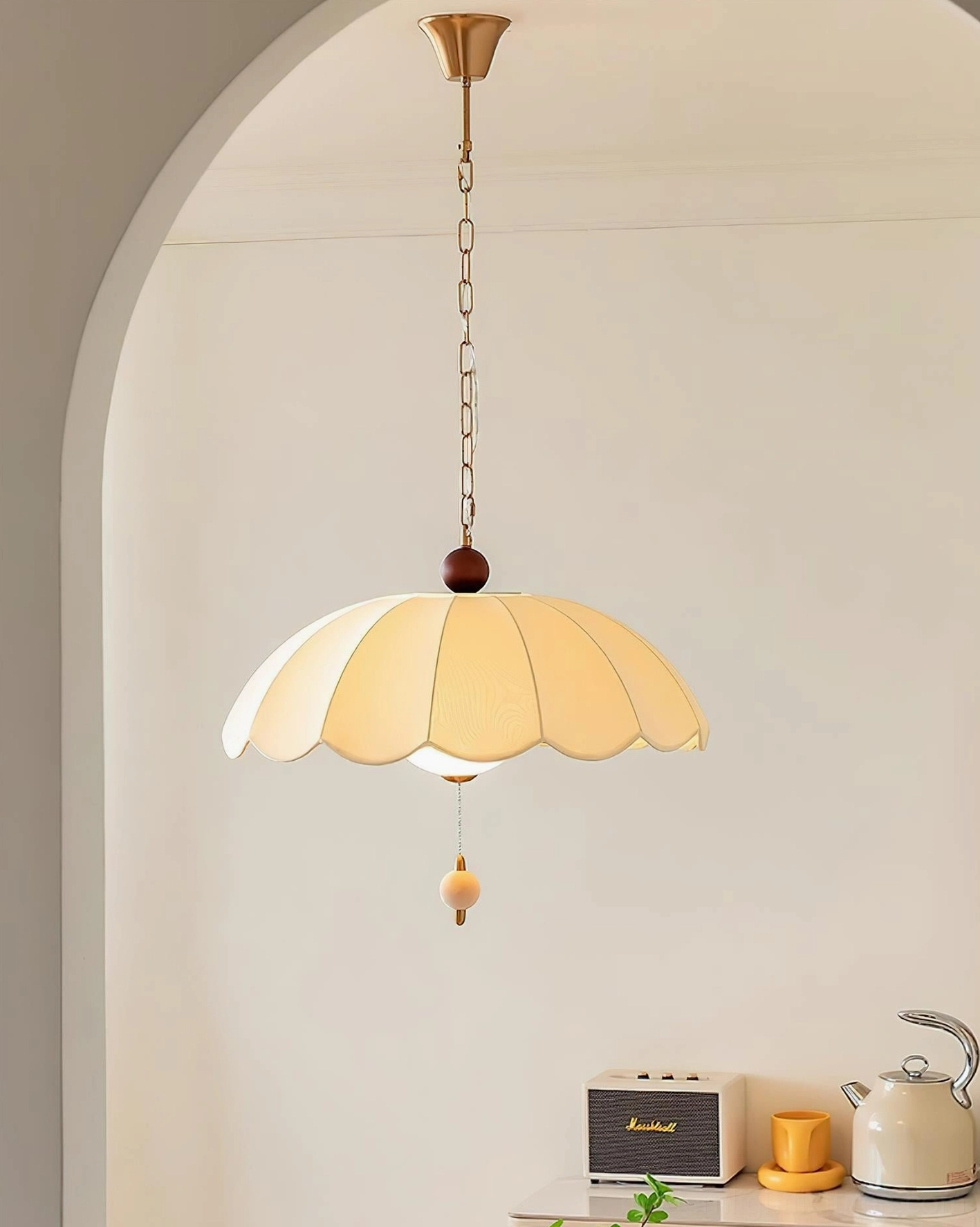 Paralune scalloped pendant lamp in light tan with brass hardware, installed in arched doorway dining space