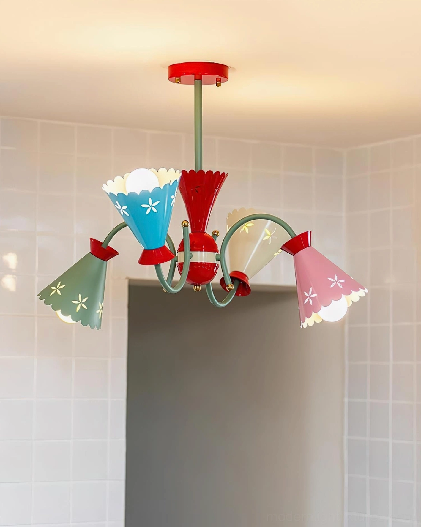 Illuminated pastel chandelier in bathroom with tiled walls showing lit light bulbs in all five arms with classic soft pastel color palette