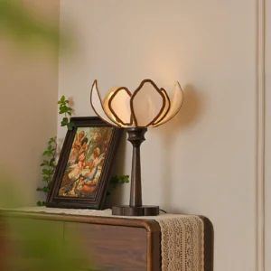 Lit Pauline vintage table lamp on antique dresser with framed artwork and green plant decoration, warm ambient lighting